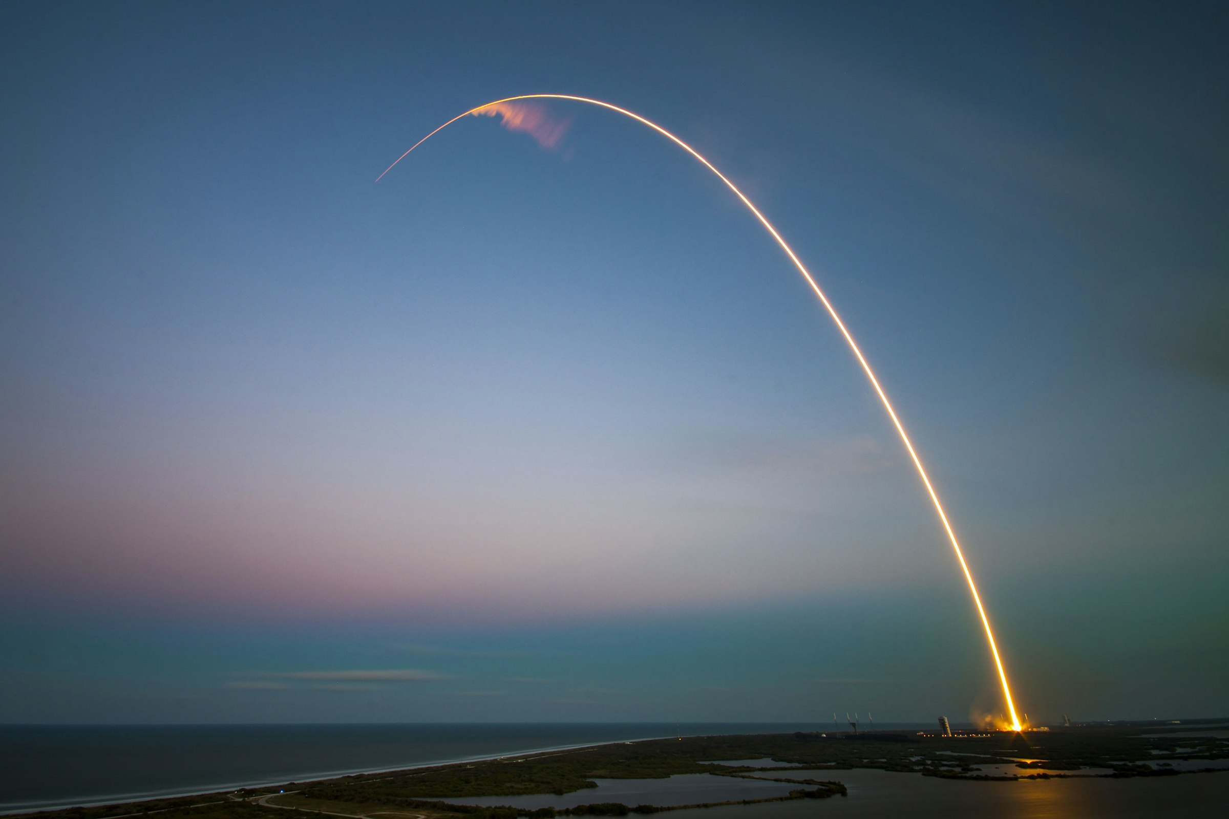 A rocket ascends through the upper atmosphere at dawn